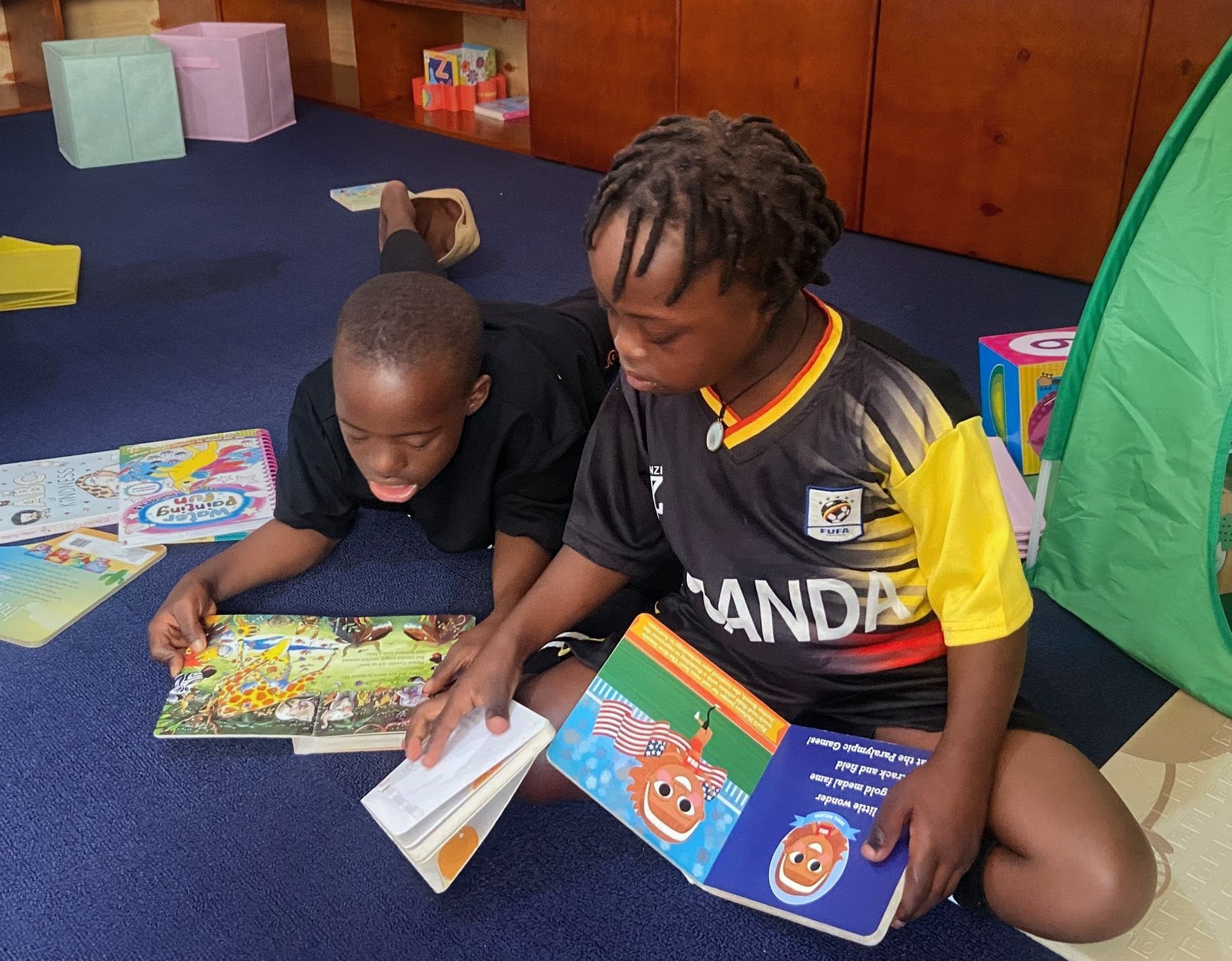 Two children reading picture books together in a learning space.