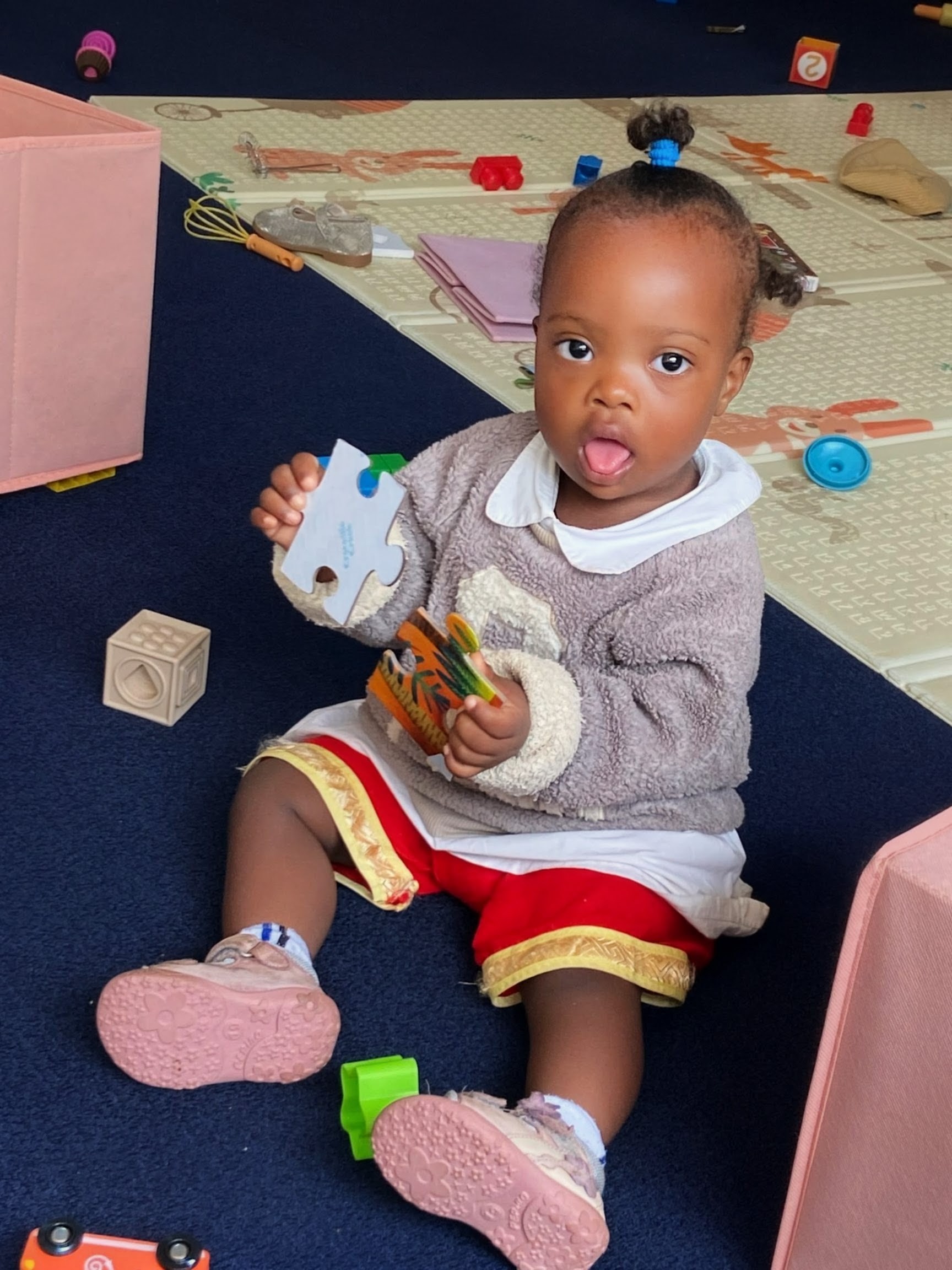 A young child playing with puzzle pieces in an early learning space.