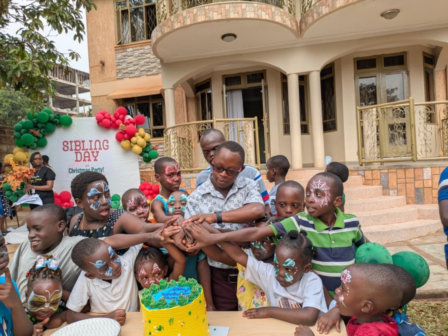 Children gathered around a cake at a sibling day celebration.