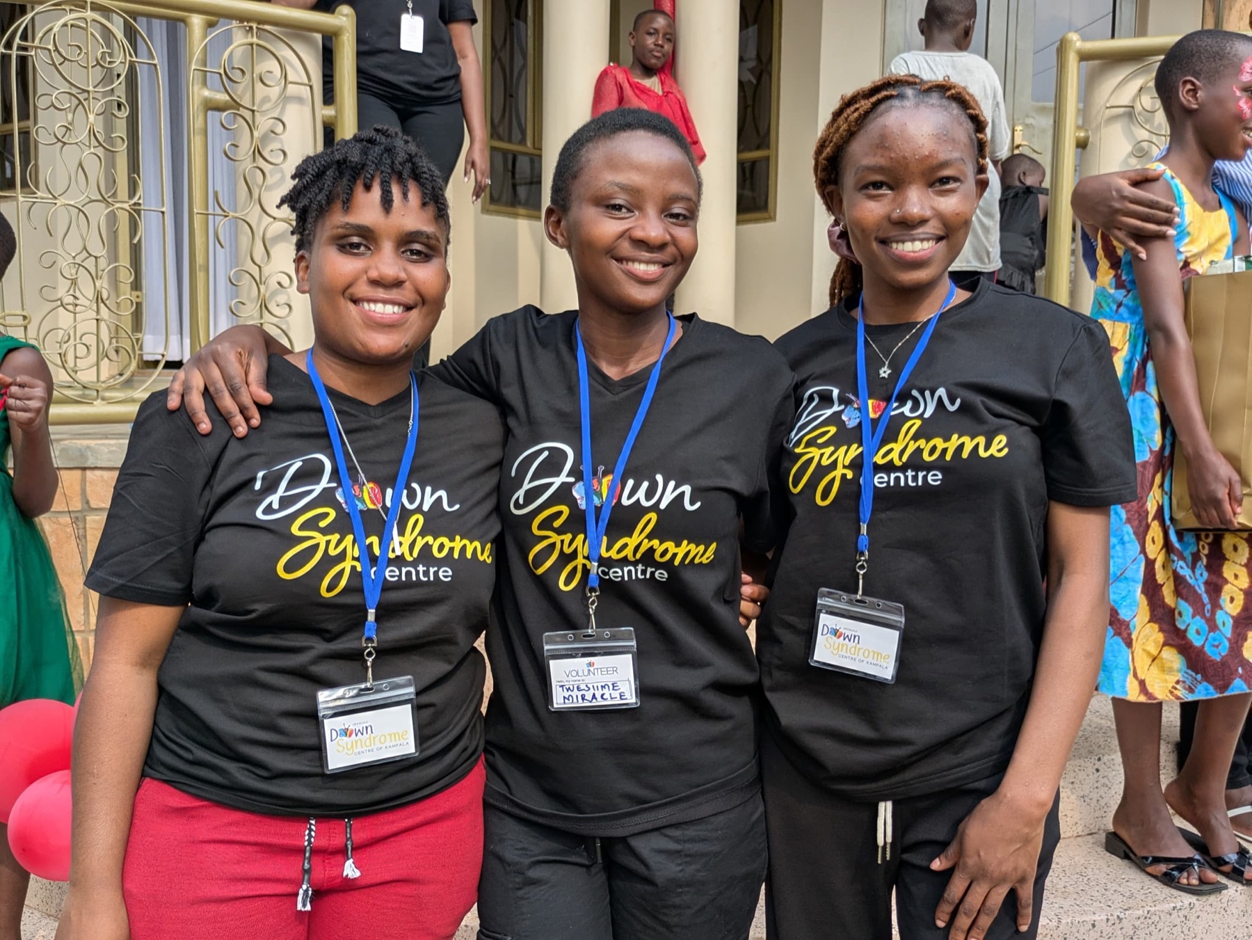 Volunteers smiling together in Down Syndrome Centre shirts.